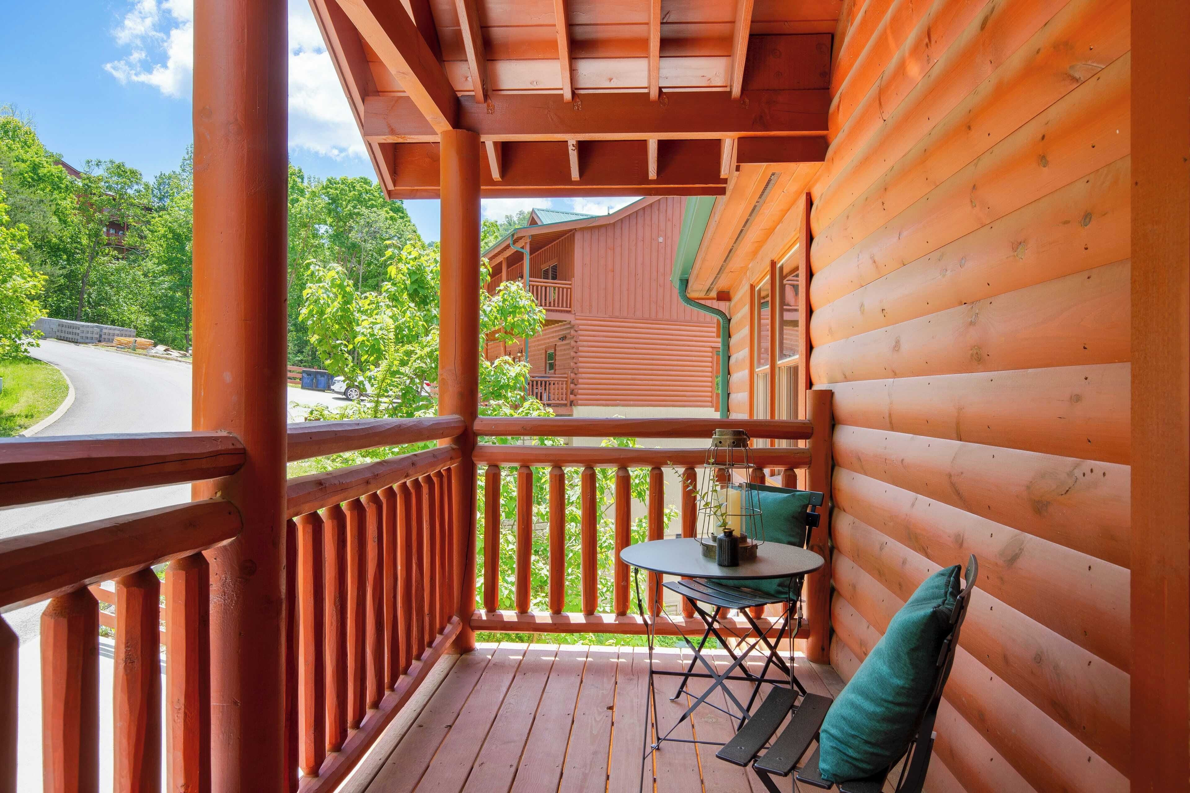 A wooden deck with a table and chairs, overlooking a road and a building.