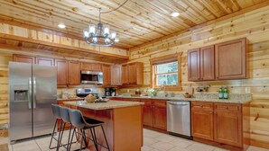 Una cocina con paneles de madera, electrodomésticos de acero inoxidable y una zona de bar con taburetes.