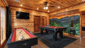 A wooden-floored room with a foosball table, pool table, and a television mounted on the wall. - Evergreen Lodge by Avantstay Indoor Heated Pool + Game Room + Movie Theater + Hot Tub Mtn Views + Pigeon Forge (Sevierville)