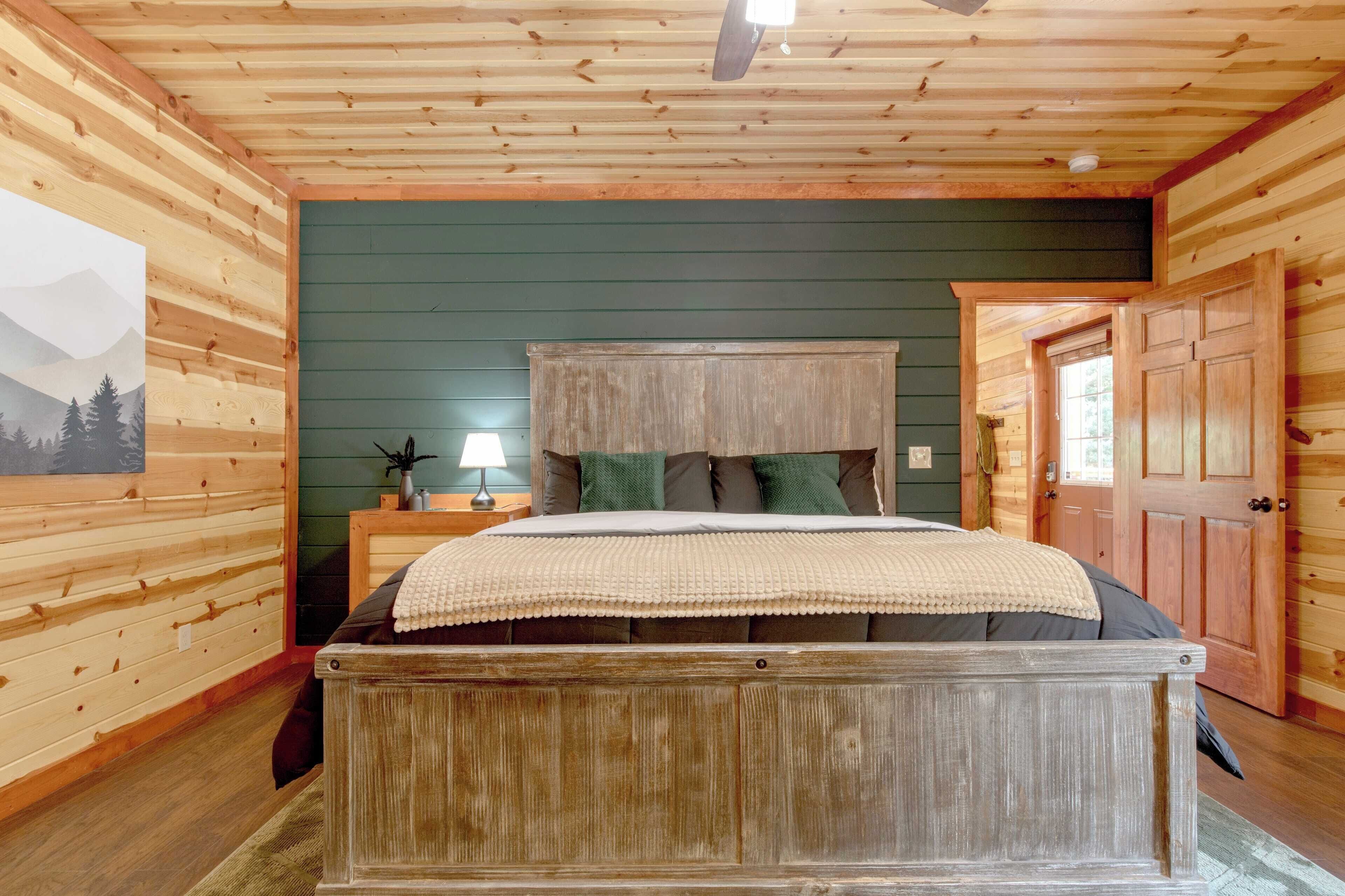 A wooden-paneled bedroom with a bed, a nightstand, a lamp, and a door.