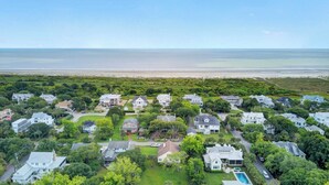 An aerial view of a coastal residential area with houses, green lawns, and a beach in the background. - Ion by Avantstay Walk to Beach, Dining, Shopping Central Location Deck (Sullivan's Island)