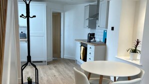 A modern kitchen with white cabinets, a round dining table with four chairs, and a wooden floor. - Bay View House - a countryside retreat close to Snowdon and Zipworld! (Bangor)