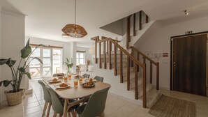 Un comedor con una mesa de madera, sillas y una escalera con barandillas de madera.