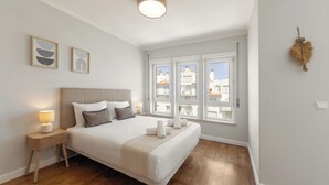 Un dormitorio con cama, mesitas de noche, una ventana con vistas y decoración en la pared.