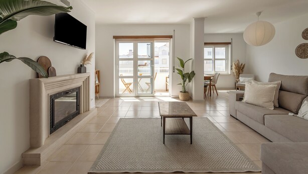 Una sala de estar con chimenea, un sofá, una mesa de centro y un televisor montado en la pared.