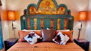 A bed with a decorative headboard, multiple pillows, and two bedside lamps.