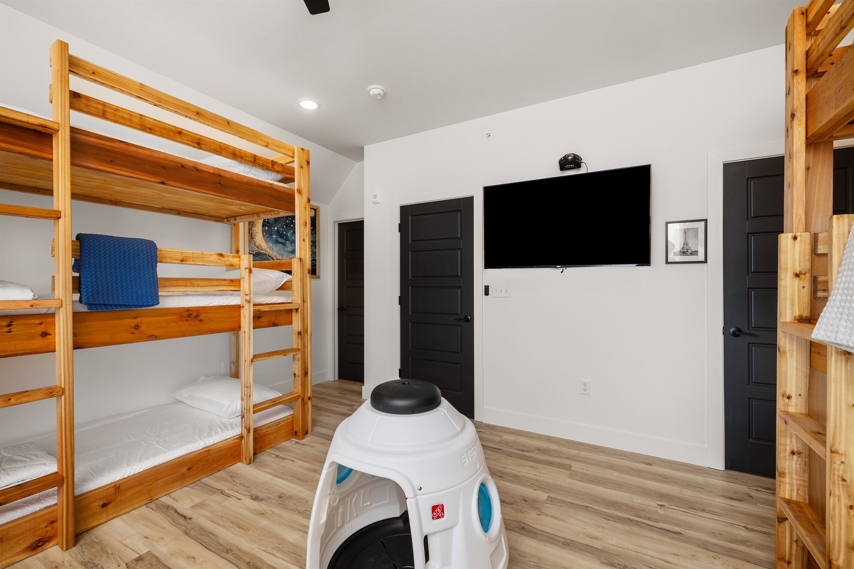 A bunk bed room with a television and a small pet carrier.