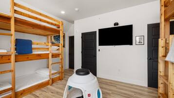 A bunk bed room with a television and a small pet carrier.