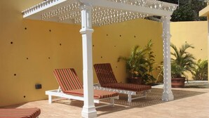 A covered outdoor seating area with white columns and striped cushions. - South Sea House Luxurious Apt No 2 (Cap Estate, St. Lucia)