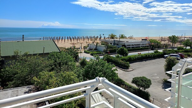 A view of a beach with a clear sky, a parking area, and some greenery. - Hotel Riviera  (Silvi)