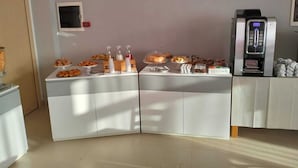 A breakfast buffet with various pastries and beverages, a coffee machine, and a small TV screen on the wall. - Hotel Riviera  (Silvi)