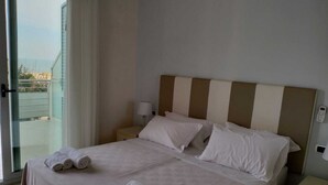 A hotel room with a bed, a nightstand, a lamp, and a view of the outside. - Hotel Riviera  (Silvi)