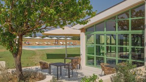 A poolside area with lounge chairs and umbrellas, a dining area with tables and chairs, and a large glass door. - Tenuta Asmara Luxury Resort (San Miniato)