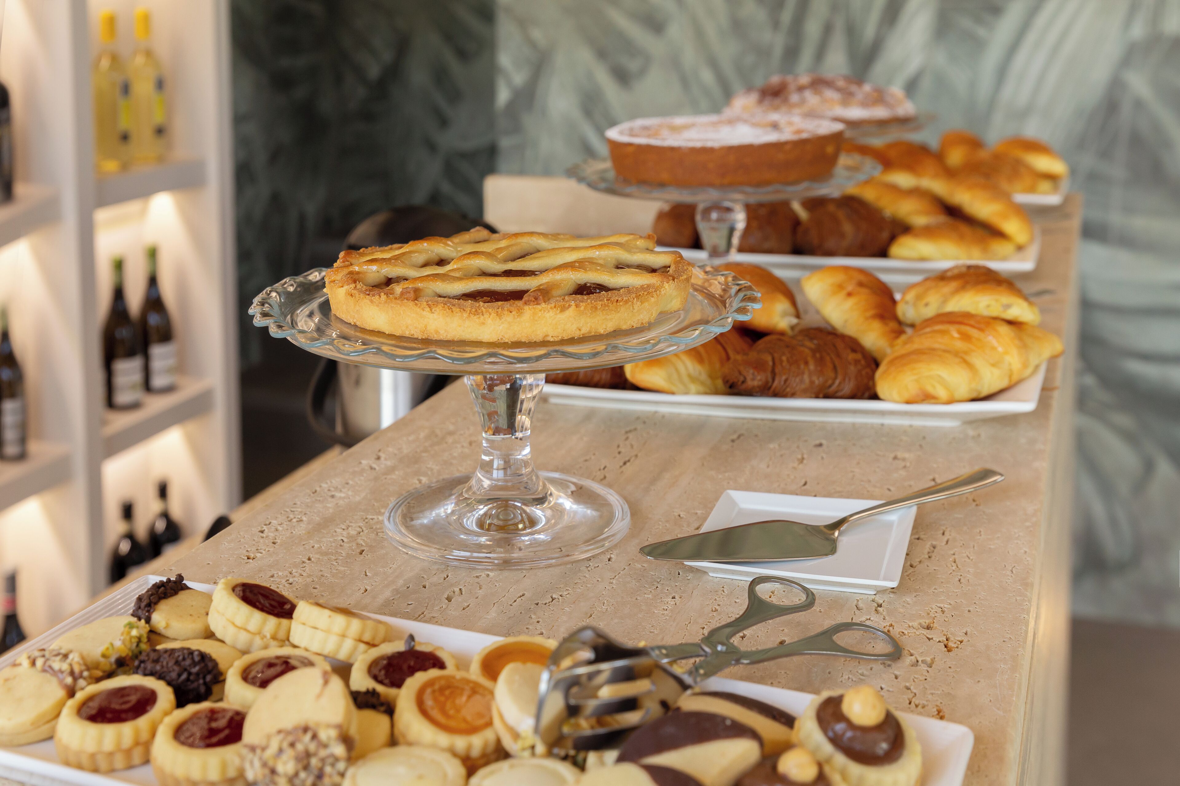 A buffet table with various pastries and desserts, including tarts, croissants, and cookies.