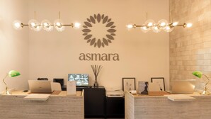 A reception desk with a logo, a television, and a desk lamp. - Tenuta Asmara Luxury Resort (San Miniato)