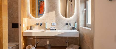 A modern bathroom with a large vanity, two oval mirrors, a built-in shower, and a towel rack.