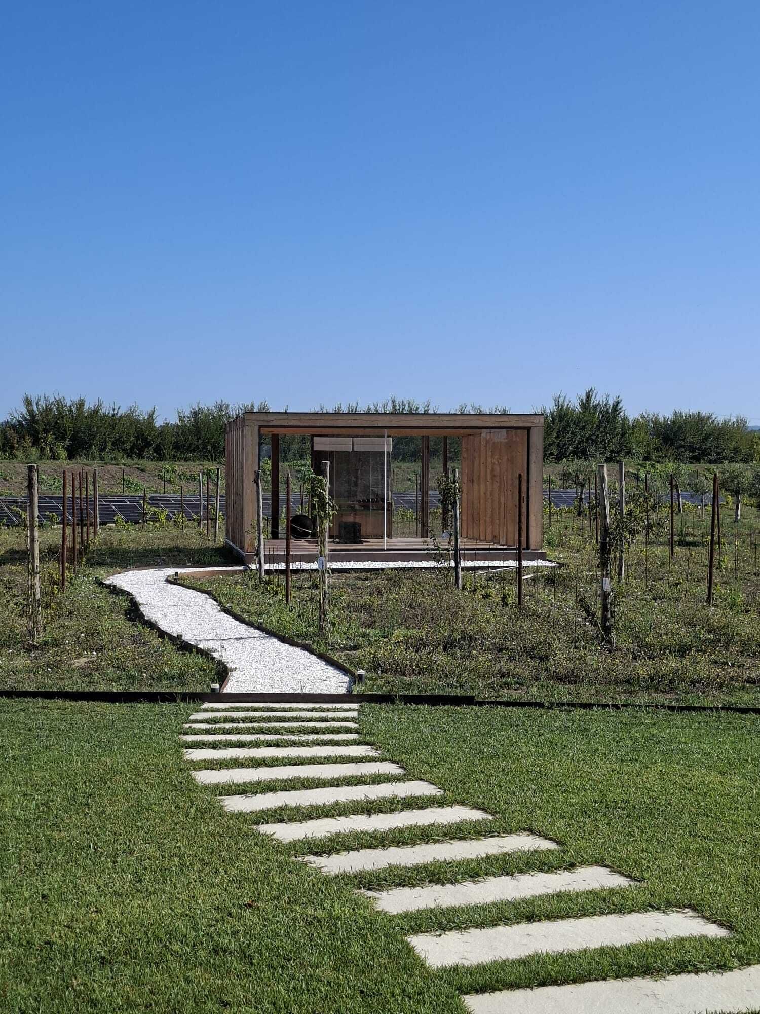 A modern building with a glass facade, surrounded by a garden with a stone pathway leading to it.