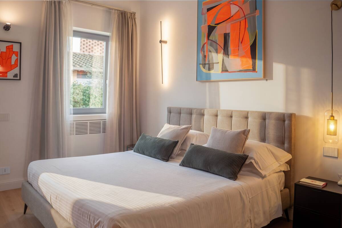 Un dormitorio moderno con una cama grande, cabecera y un cuadro abstracto colgado en la pared.