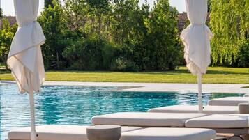 Una piscina al aire libre de temporada, sombrillas