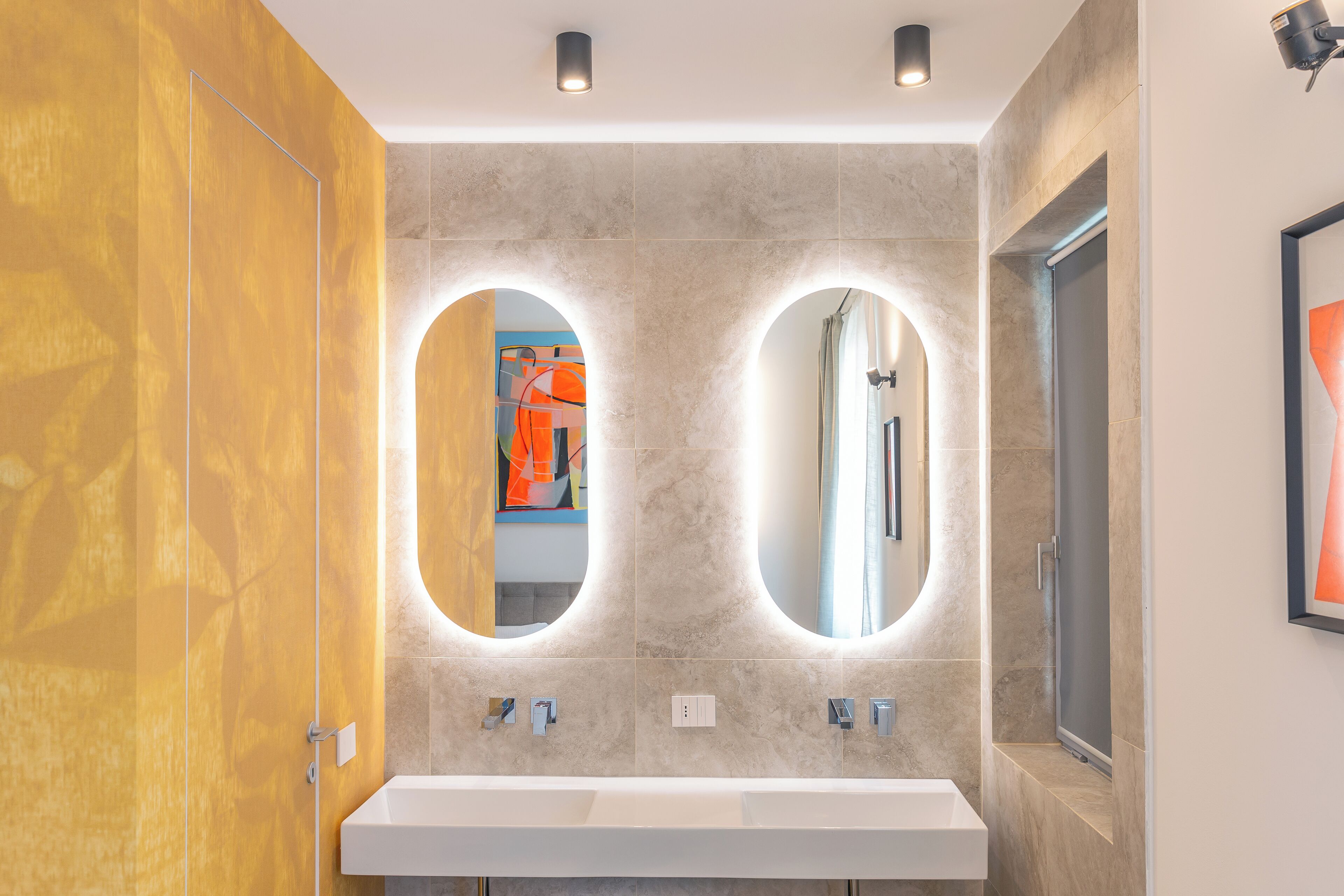 A modern bathroom with two sinks, a large mirror, and a shower.