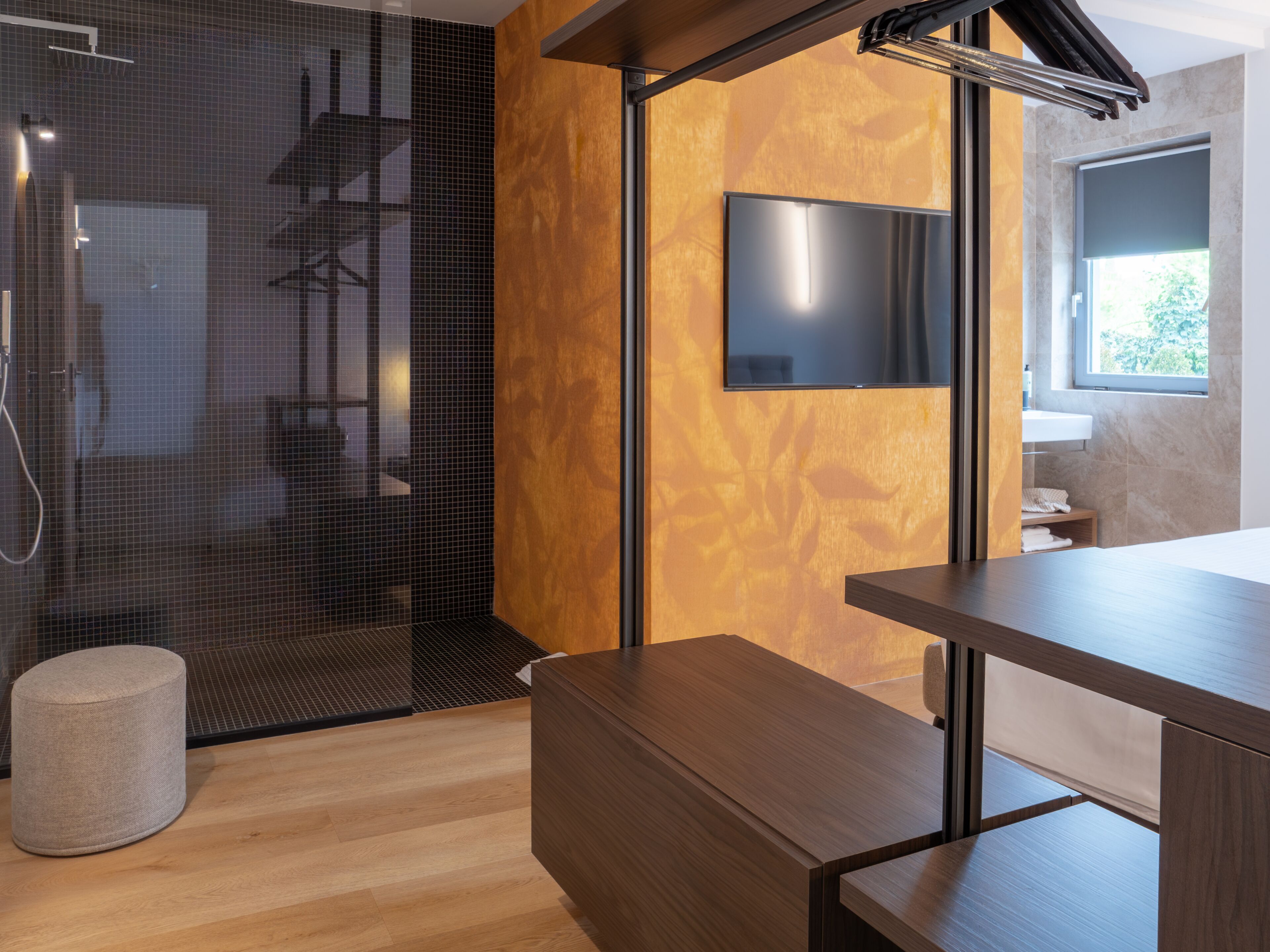 A modern bathroom with a shower, a wooden vanity, a sink, and a television mounted on the wall.