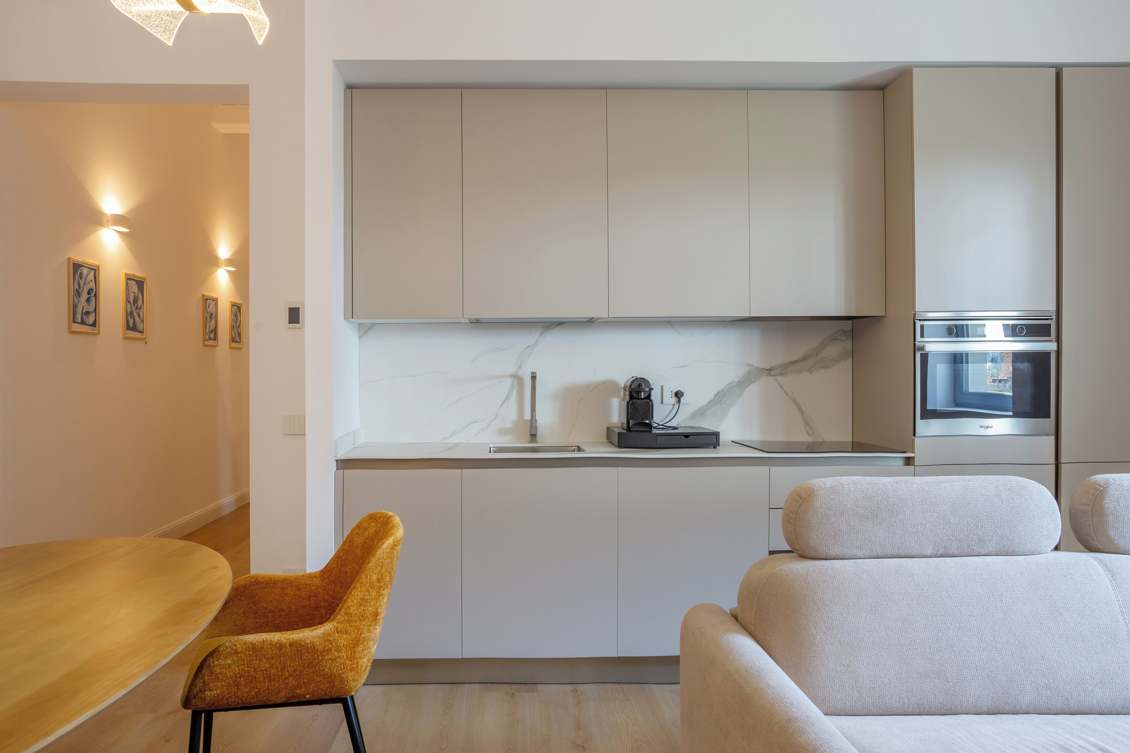 A modern kitchen with white cabinets, a marble countertop, and a built-in oven.
