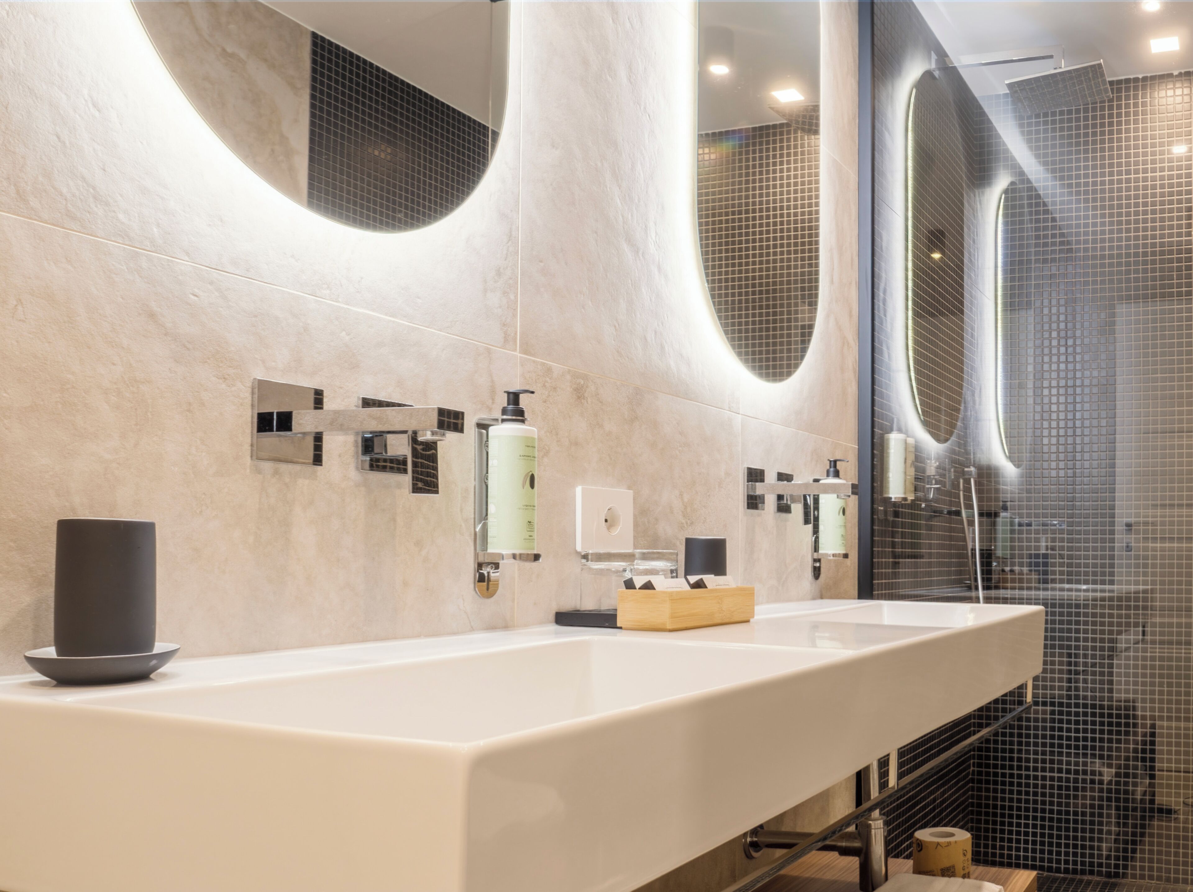A modern bathroom with a large mirror, a sink, and a shower area.