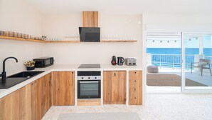 A modern kitchen with wooden cabinets, a built-in oven, and a microwave. There is a balcony with a view of the sea. - Stunning Brand New Villa Sea View (la Coveta Fumada)