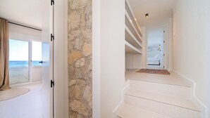 A modern interior with a stone accent wall, a staircase, and a view to a balcony. - Stunning Brand New Villa Sea View (la Coveta Fumada)