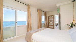 A bedroom with a large bed, a view of the sea through a sliding door, and a plant by the window. - Stunning Brand New Villa Sea View (la Coveta Fumada)