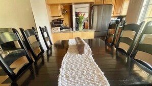 A dining table with a white table runner, surrounded by black chairs.