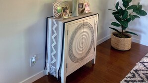 A corner of a room with a white cabinet, two round mirrors, a potted plant, and a patterned rug.