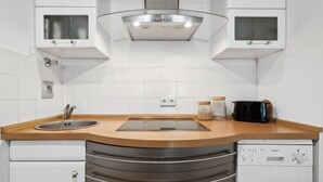 Une cuisine moderne avec des armoires blanches, un évier en acier inoxydable, un four encastré et un grille-pain.