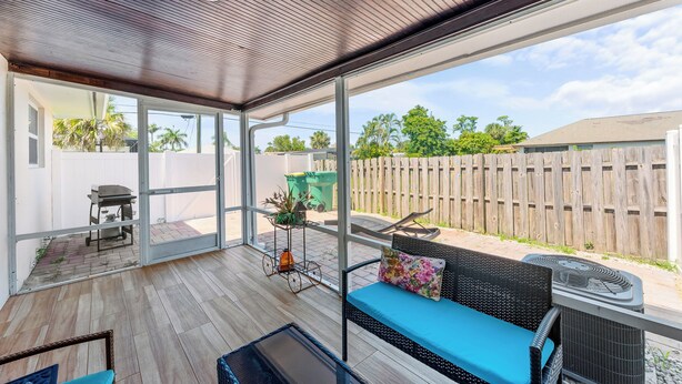 Un patio couvert avec vue sur une clôture en bois et des palmiers.