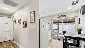 Un couloir d’hôtel avec une pancarte indiquant « Point de rencontre », un tableau d’affichage et des tableaux encadrés accrochés au mur.