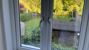 Una finestra con vista su un giardino e un portone garage.