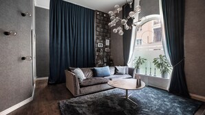 En moderne stue med en modulsofa, et rundt sofabord og et stort vindue med gardiner.