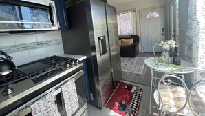 A modern kitchen with stainless steel appliances, dark blue cabinets, and a dining area with a table and chairs.