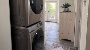A laundry room with stacked washers and dryers, a wooden cabinet, and a patterned rug.