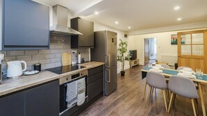 A modern kitchen with a central island, built-in oven, and a dining area with a table and chairs.