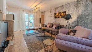 A modern living room with a sofa, coffee table, and a floor lamp. There is a concrete wall with a decorative piece and a door leading to a balcony.