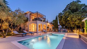 A modern house with a swimming pool, outdoor seating, and a balcony.