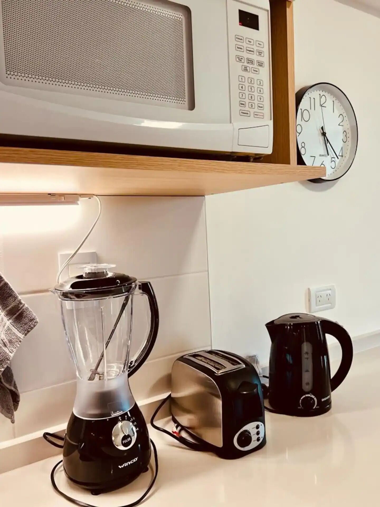 Een keuken met een magnetron, broodrooster, waterkoker en blender op het aanrecht.