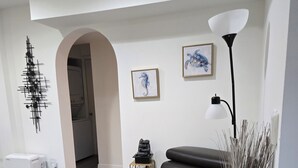 Ein modernes Wohnzimmer mit einem dunkelbraunen Ledersofa, einer Stehlampe und einer Zimmerpflanze.