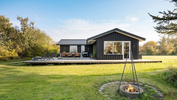 A modern house with a deck, outdoor seating, and a fire pit.