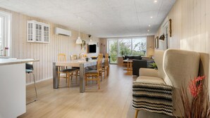 A spacious living area with a dining table, chairs, a sofa, and a TV.