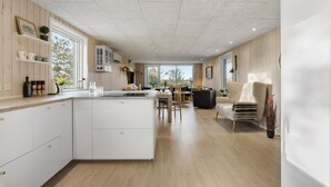 A spacious kitchen with a central island, wooden flooring, and a dining area with a sofa and chairs.