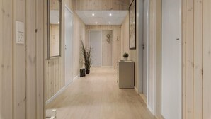 A hallway with wooden walls and a light-colored floor, leading to a door at the end.