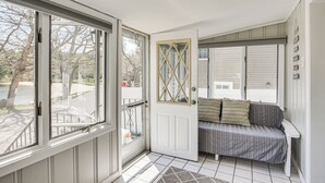 Una habitación con puerta corrediza de vidrio, un banco acolchado y vistas al exterior.