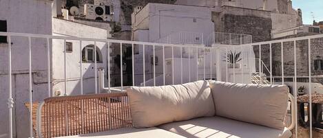 Un sofá blanco de exterior en una terraza en la azotea con vistas a un paisaje urbano histórico.